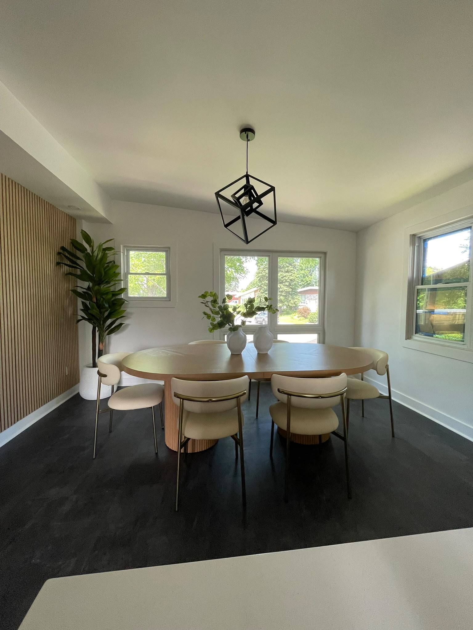 Bright dining room with an oval wood table, six upholstered chairs, and large windows