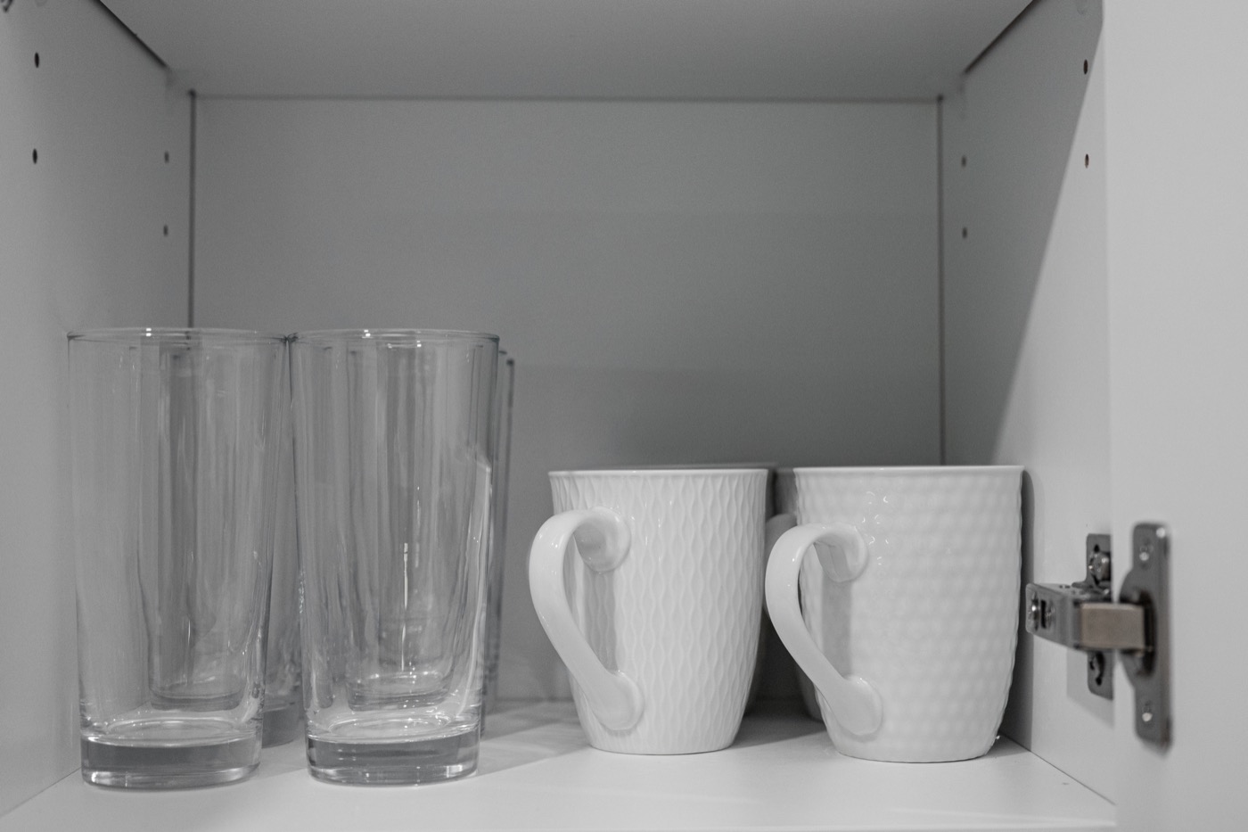 Glasses and mugs arranged neatly inside a kitchen cabinet