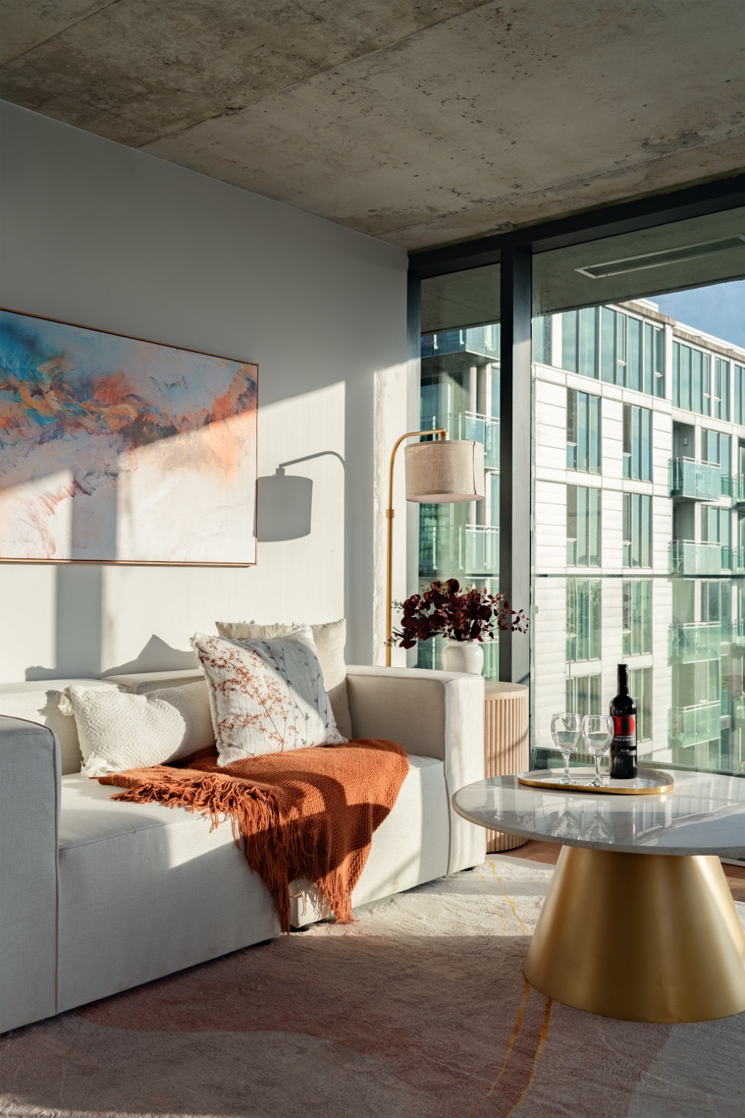 Warm furnished living room with city windows and evening light