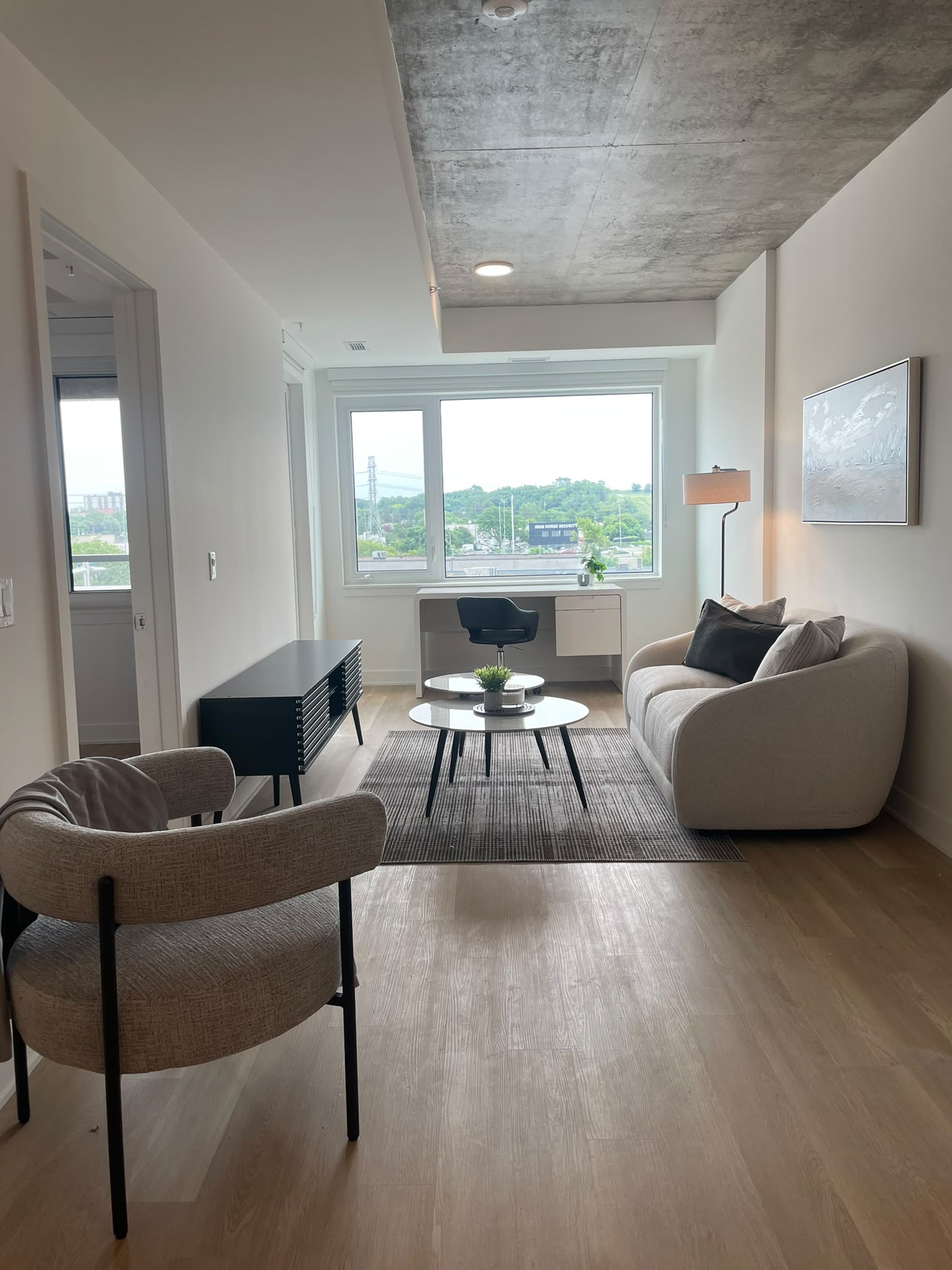 Finished apartment living room with seating, tables, lamps, and a workspace